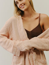 Woman wearing a beige robe over a brown top against a plain background